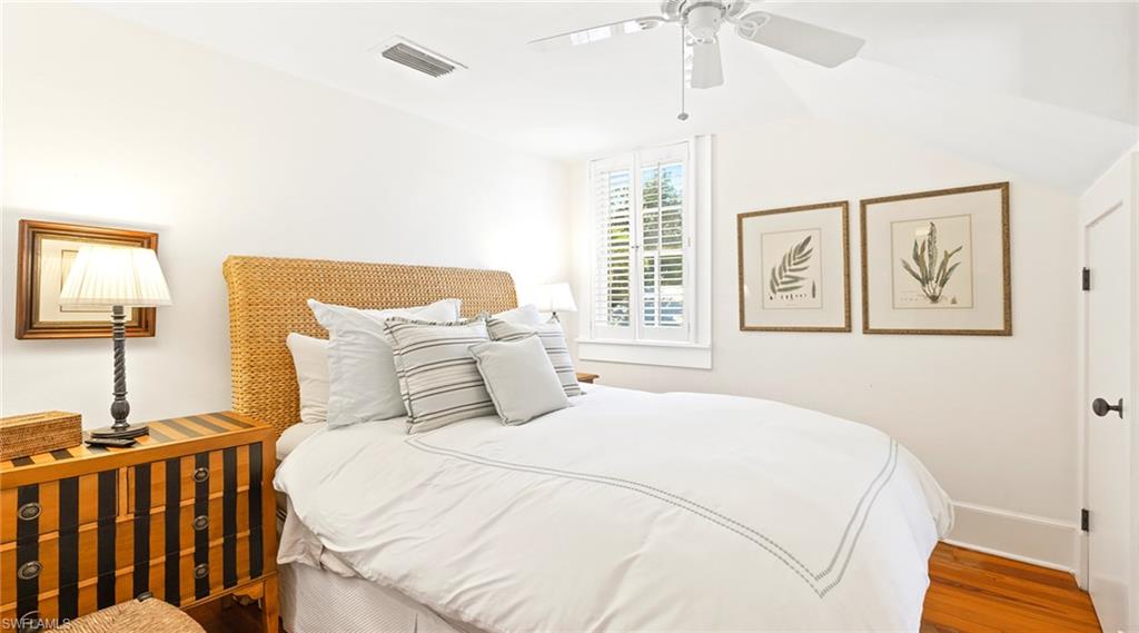 Bedroom with a ceiling fan, wood finished floors, and vaulted ceiling