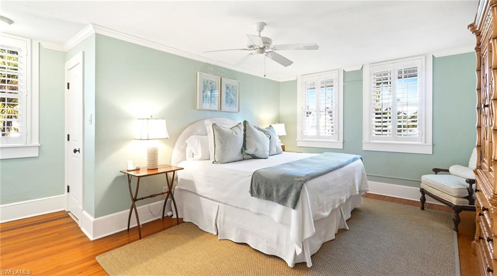 Bedroom featuring crown molding, multiple windows, light wood-style floors, and a ceiling fan