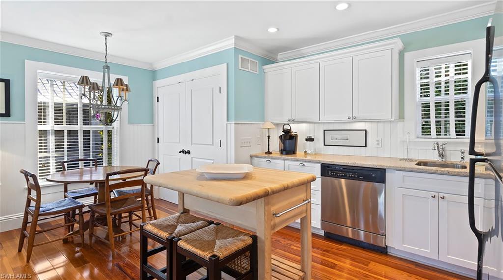 Kitchen with white cabinets, stainless steel dishwasher, refrigerator, crown molding, and light stone counters