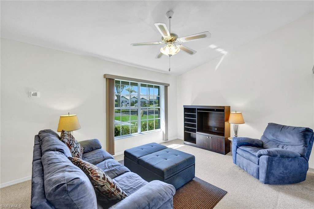 Living area with light carpet, lofted ceiling, and a ceiling fan