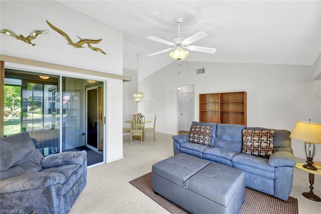 Carpeted living room with ceiling fan and high vaulted ceiling