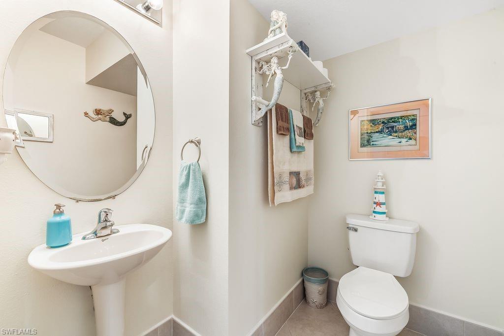 Half guest bathroom with tile patterned flooring, toilet, and pedestal sink