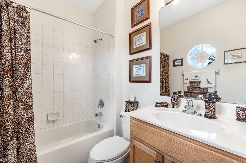 En-suite Guest Bathroom featuring a tiled shower / bathtub combination, large vanity, and tiled floors
