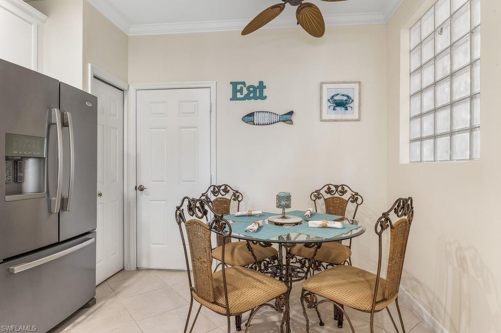 Eat-in Kitchen featuring appliances with stainless steel finishes, sleek white cabinetry, light tile patterned floors, ornamental molding, and light granite counters and backsplash