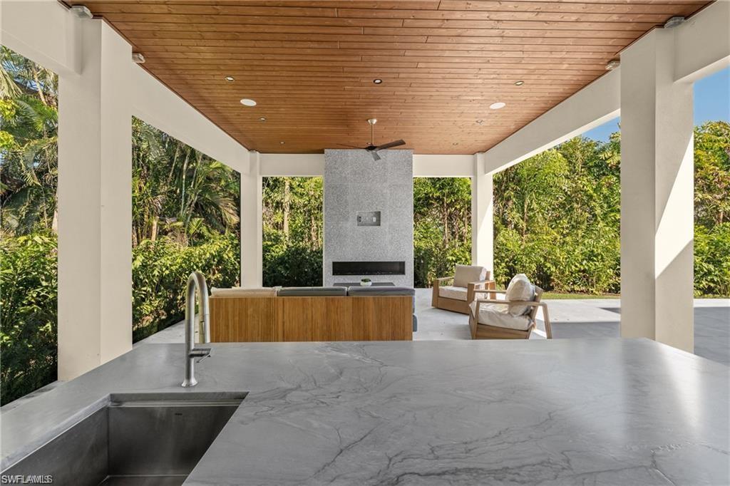 View of patio / terrace featuring an outdoor living space with a fireplace and view of scattered trees