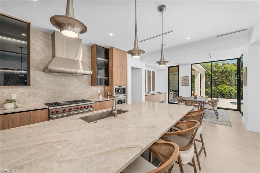 Kitchen with modern cabinets, light stone countertops, tasteful backsplash, and recessed lighting