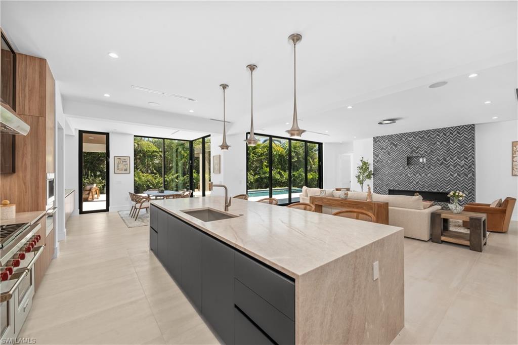 Kitchen featuring modern cabinets, an accent wall, hanging light fixtures, recessed lighting, and a kitchen island with sink