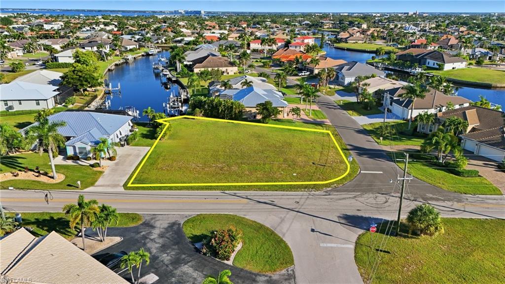 Aerial perspective of suburban area with property boundaries highlighted and a nearby body of water