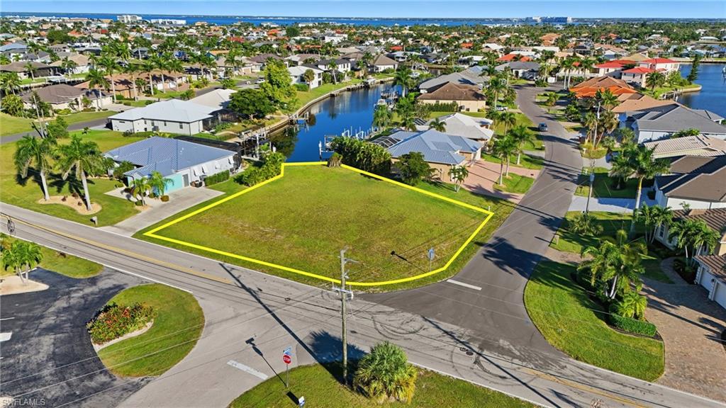 Aerial view of residential area with property parcel outlined and a nearby body of water