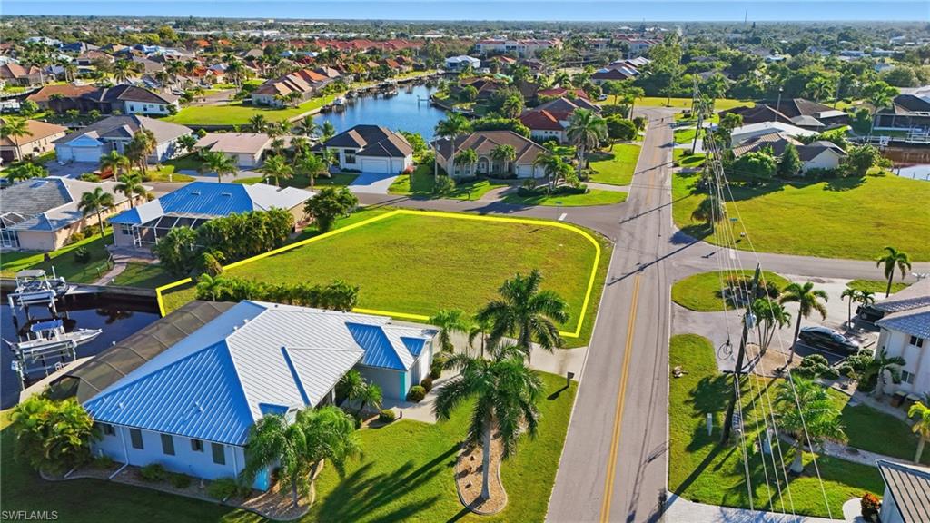 Aerial view of residential area featuring a nearby body of water and property parcel outlined