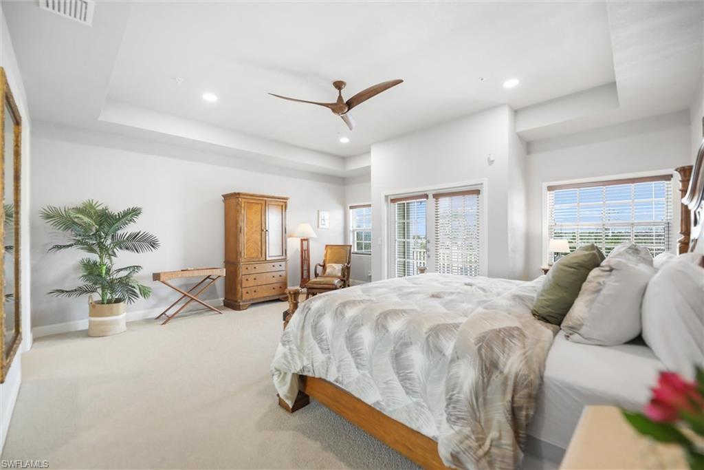 Bedroom with light carpet, recessed lighting, ceiling fan, a tray ceiling, and access to exterior
