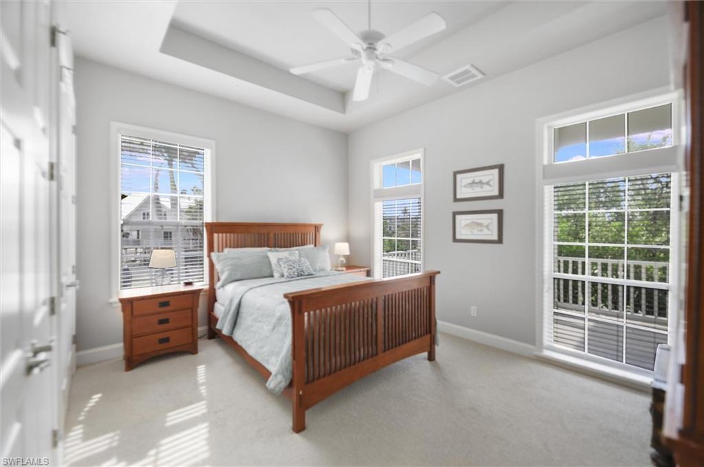 Bedroom featuring light colored carpet, a tray ceiling, and a ceiling fan
