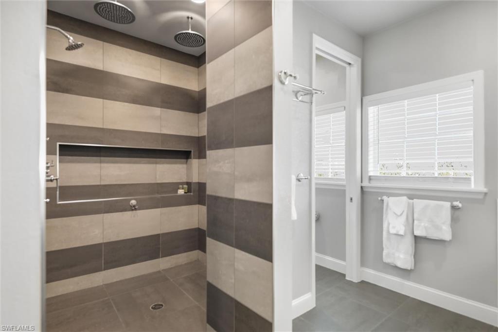 Full bathroom featuring tiled shower and baseboards