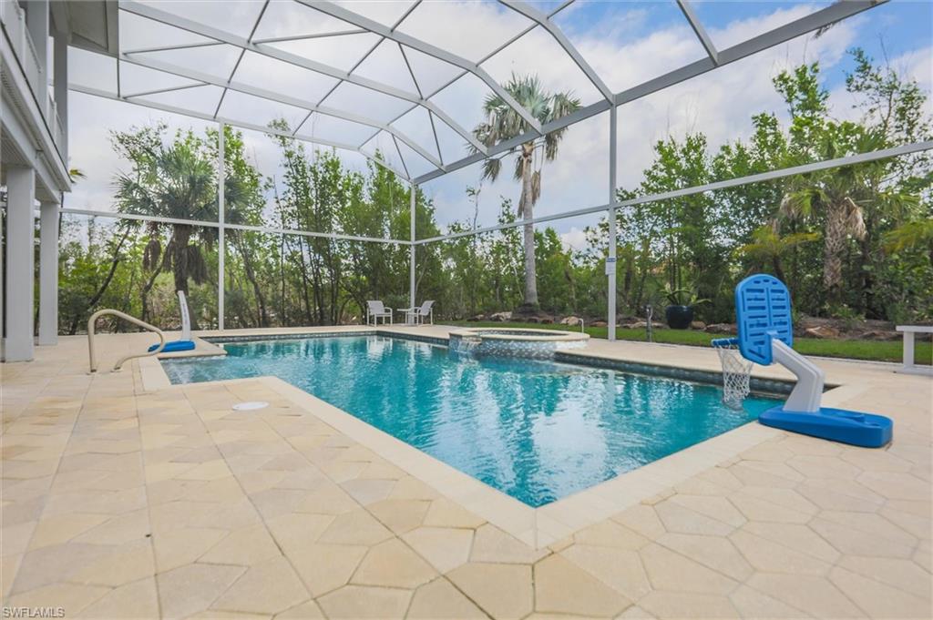 View of swimming pool featuring glass enclosure, a patio area, and a pool with connected hot tub