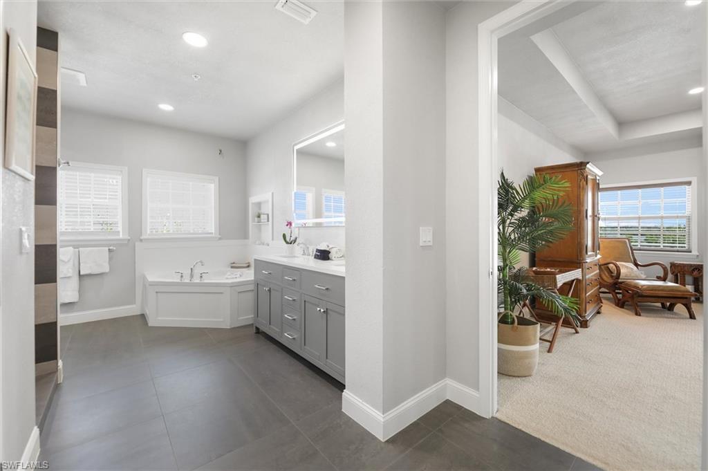 Bathroom featuring vanity, a garden tub, tile patterned flooring, and recessed lighting