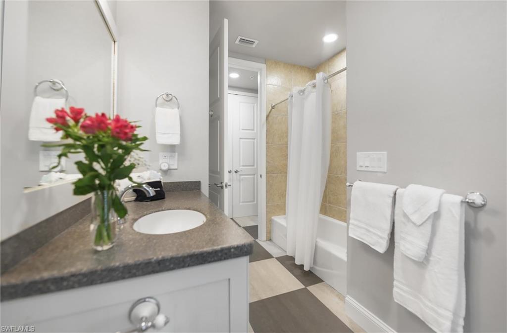Bathroom featuring vanity and shower / bathtub combination with curtain