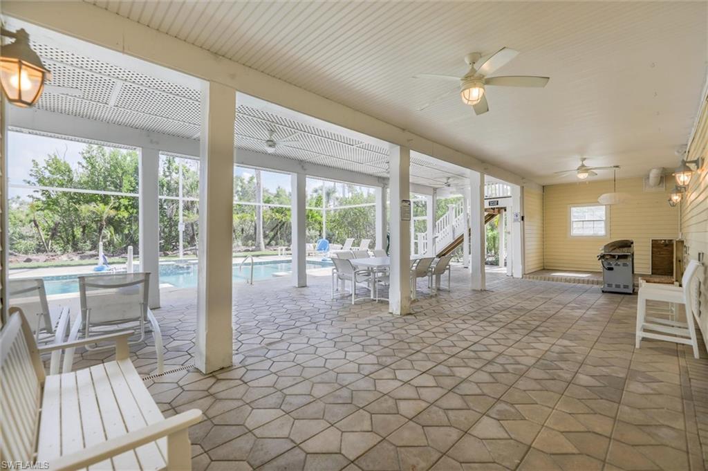 View of patio with a ceiling fan, stairs, an outdoor pool, and grilling area