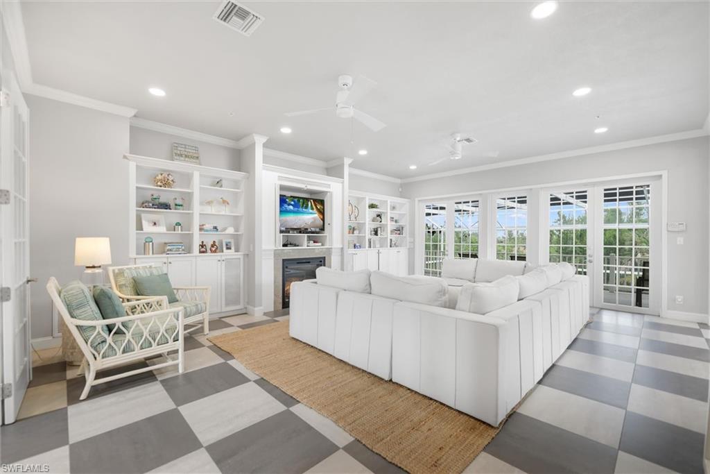 Living room with ornamental molding, recessed lighting, ceiling fan, a glass covered fireplace, and light flooring