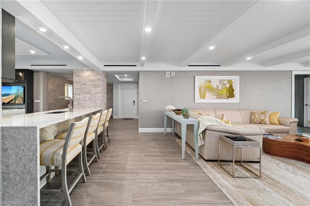 Living room with light wood-style flooring, beamed ceiling, recessed lighting, and wallpapered walls