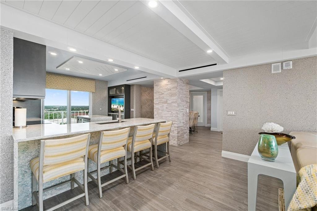 Kitchen featuring light stone countertops, beam ceiling, a kitchen breakfast bar, a peninsula, and recessed lighting