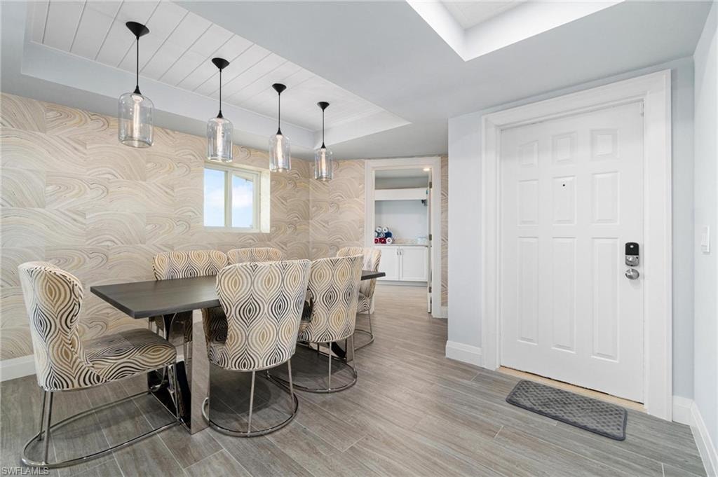 Dining space with a raised ceiling, light wood-type flooring, a skylight, and wood ceiling