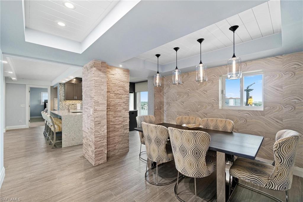 Dining space featuring a raised ceiling, light wood-style flooring, recessed lighting, and wallpapered walls