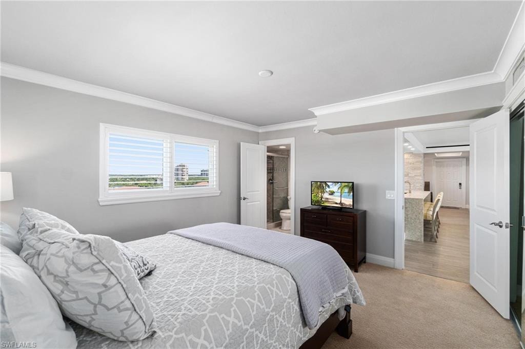 Bedroom with ornamental molding, light colored carpet, and ensuite bathroom