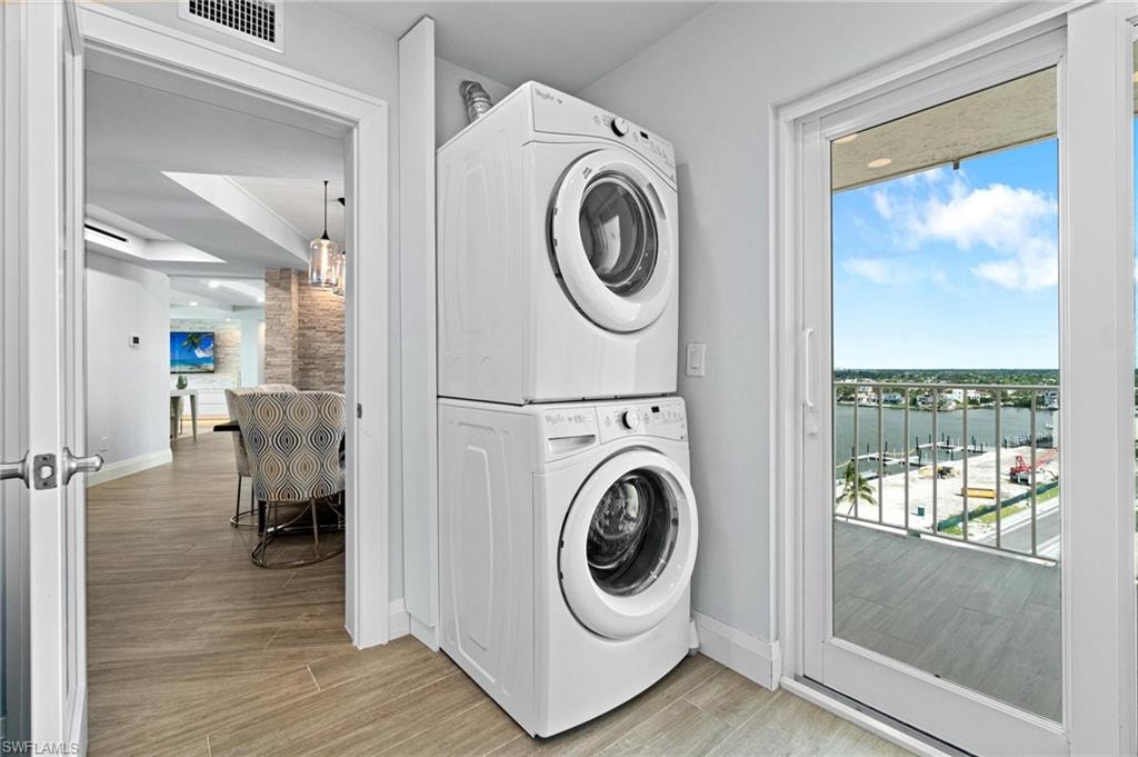 Laundry area featuring light wood-style floors and stacked washing machine and dryer