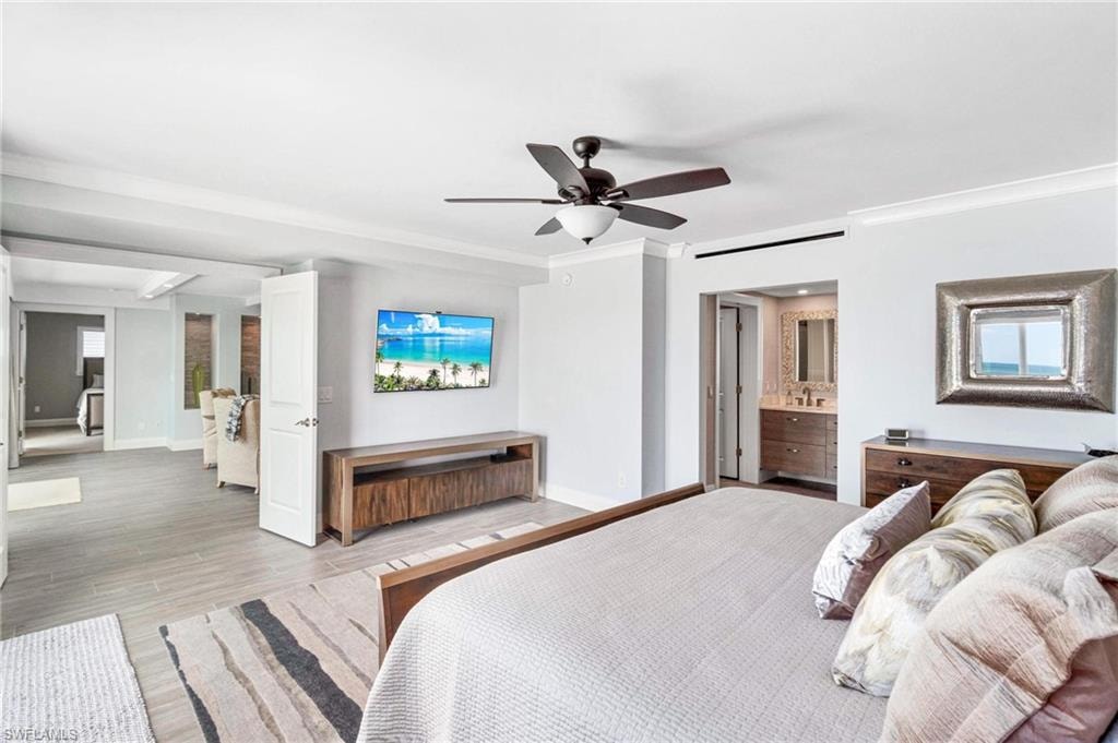 Bedroom with wood finished floors, crown molding, ceiling fan, and ensuite bathroom