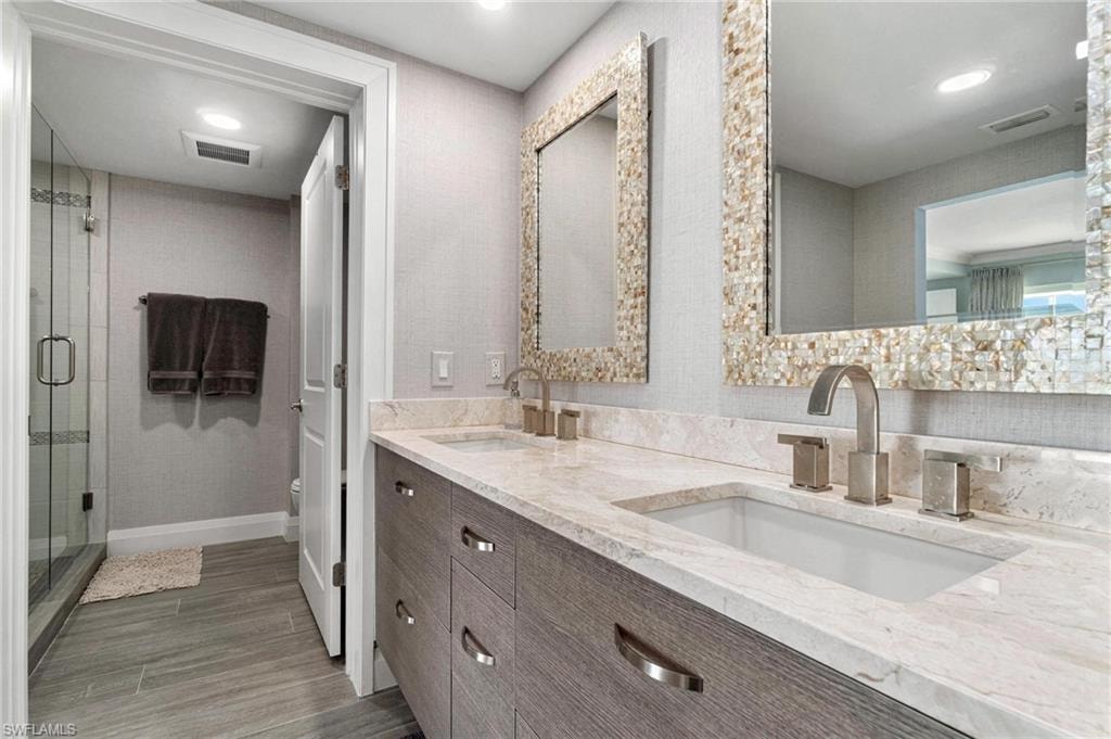 Full bathroom featuring double vanity, a shower stall, recessed lighting, and light wood-type flooring