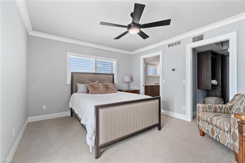 Bedroom with ornamental molding, carpet floors, connected bathroom, and ceiling fan