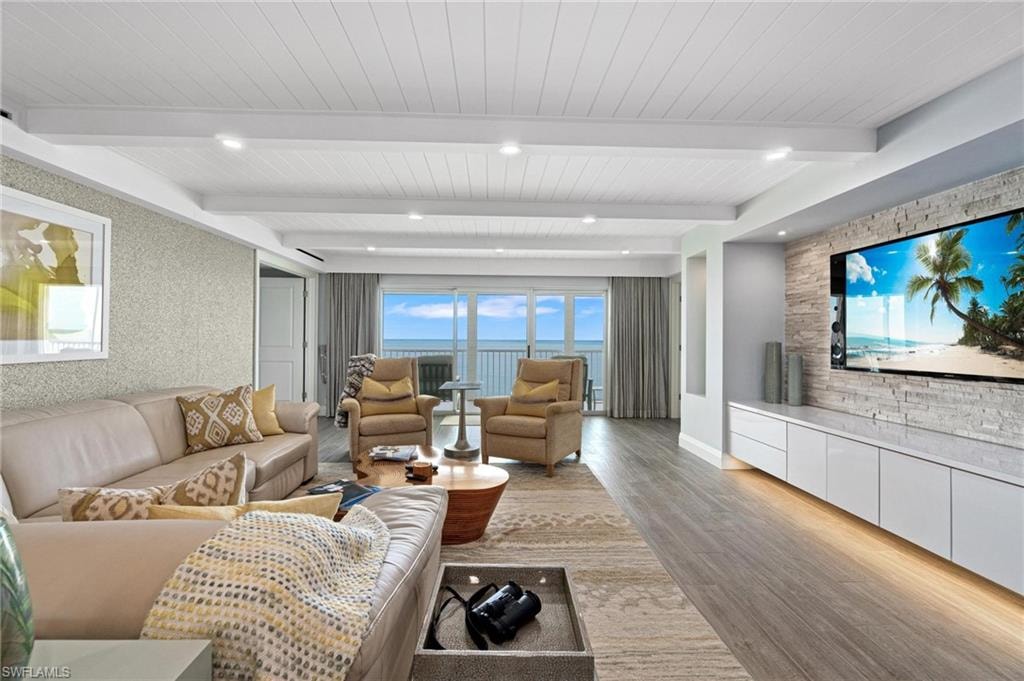 Living area featuring healthy amount of natural light, wood finished floors, and beamed ceiling
