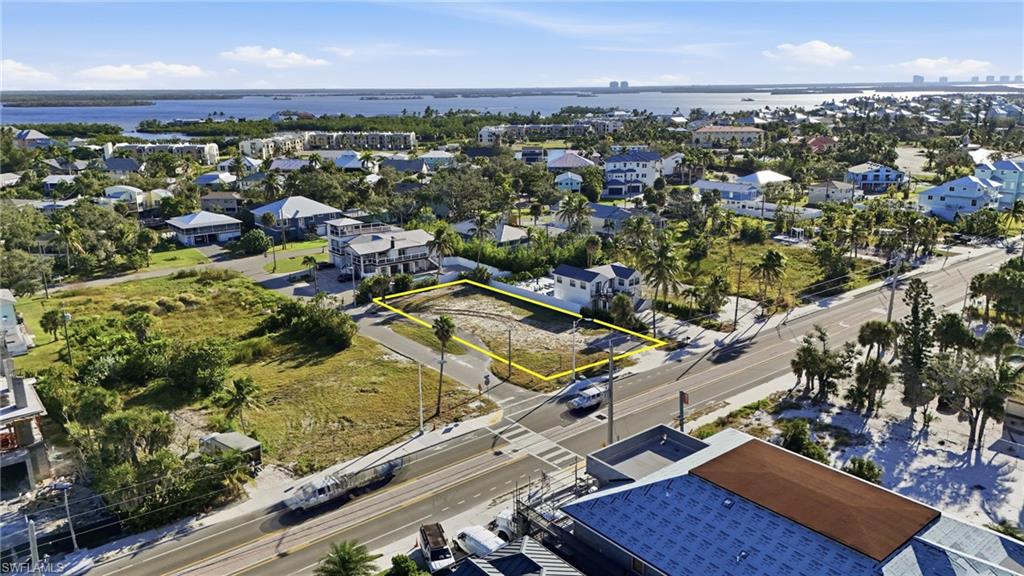 Aerial perspective of suburban area featuring property parcel outlined and a large body of water - Virtually Edited Image