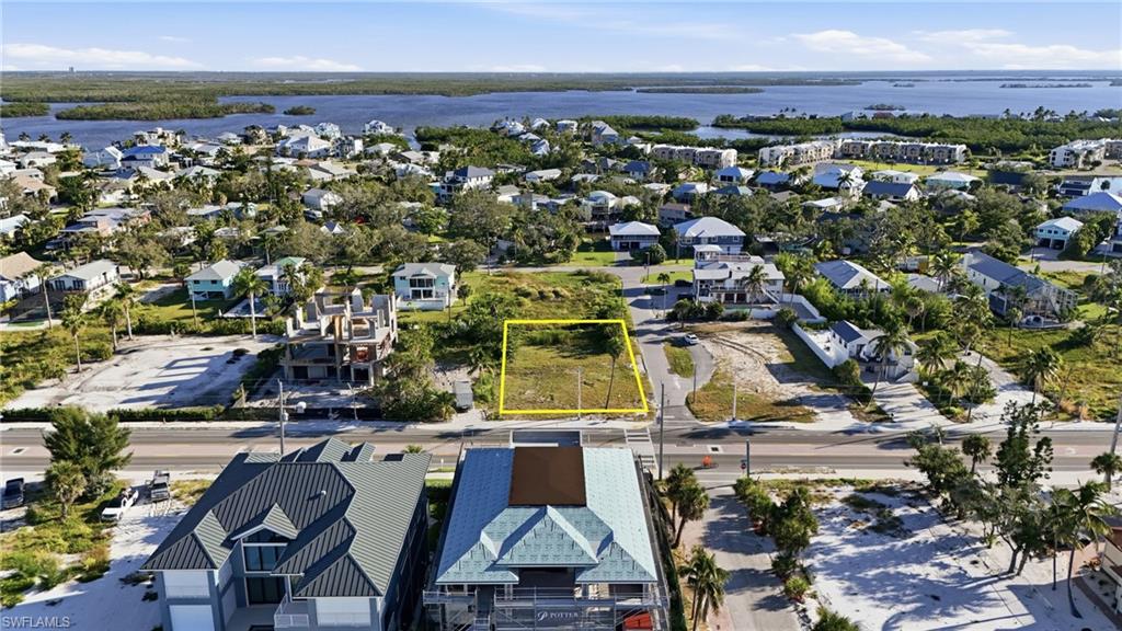Aerial view of residential area featuring property boundaries highlighted and a large body of water - Virtually Edited Image