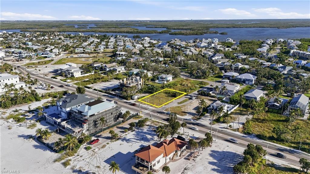 Aerial view of residential area featuring property parcel outlined and a large body of water - Virtually Edited Image