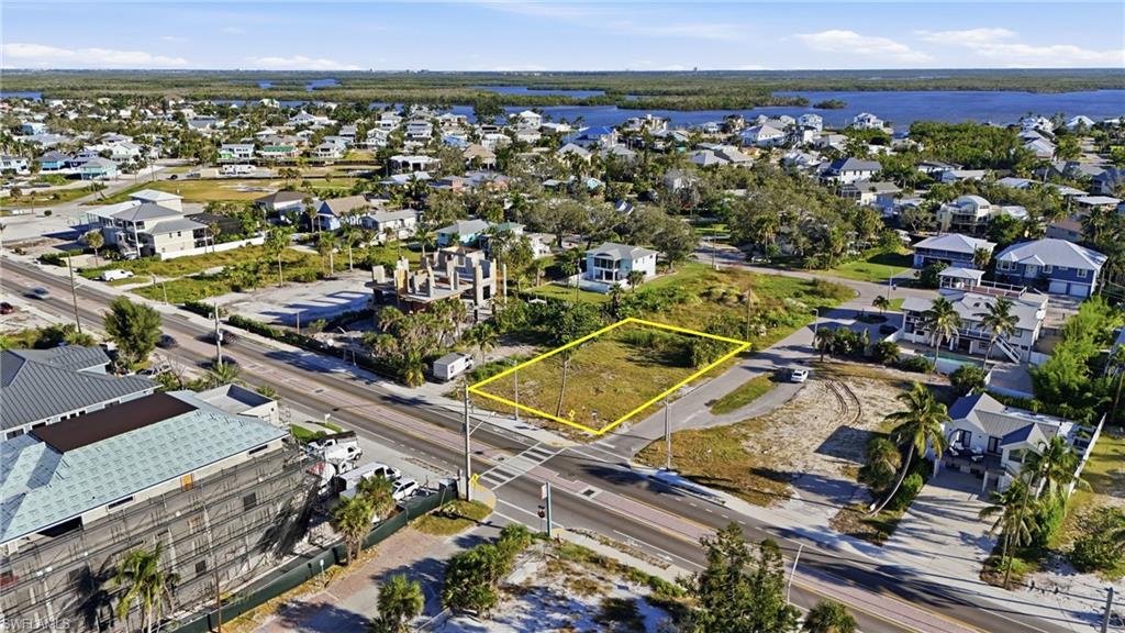 Aerial view of residential area with property parcel outlined and a nearby body of water - Virtually Edited Image