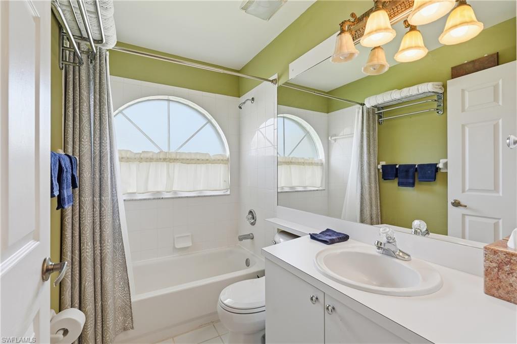 Bathroom with shower / tub combo with curtain, vanity, and light tile patterned flooring