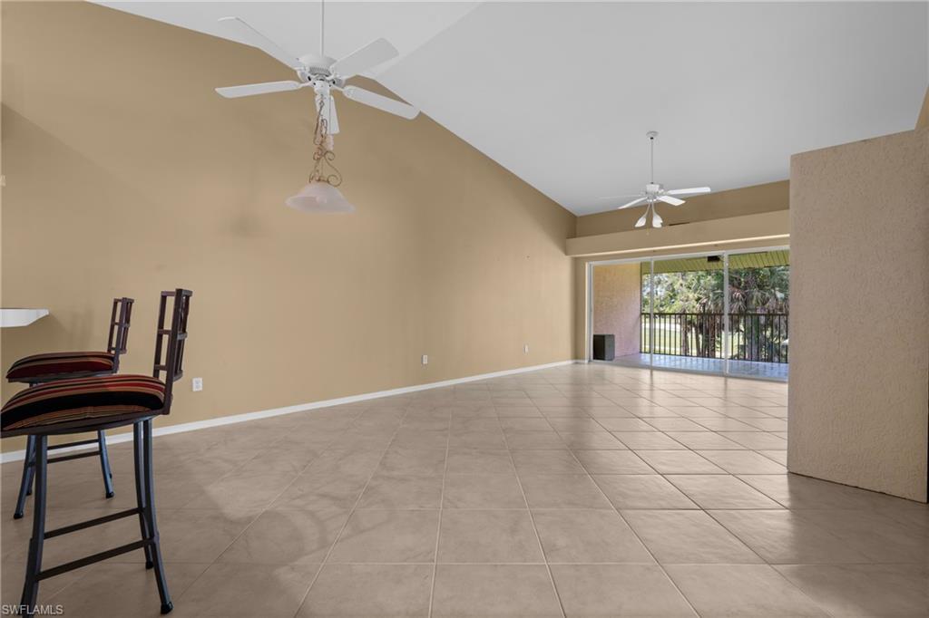Spacious room featuring vaulted ceilings, light tile flooring, and neutral wall tones