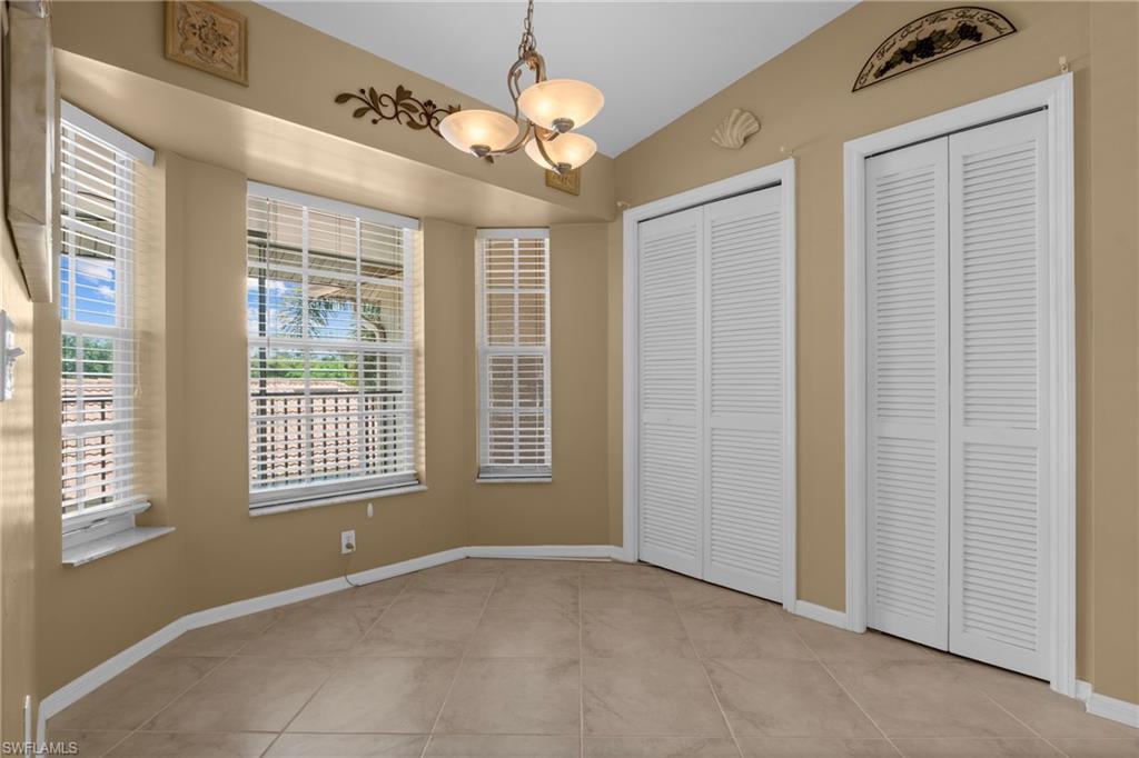 Tiled flooring throughout this space, featuring multiple windows with blinds, a ceiling-mounted light fixture, and two louvered bifold closet doors