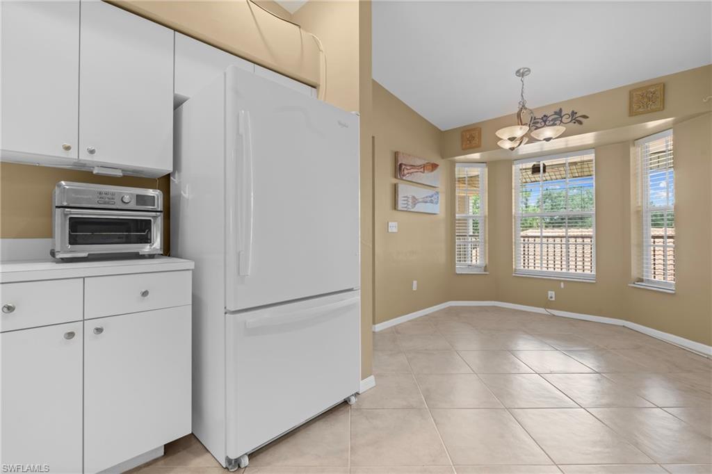 Kitchenette area featuring white cabinetry, light-toned countertops, and a white refrigerator