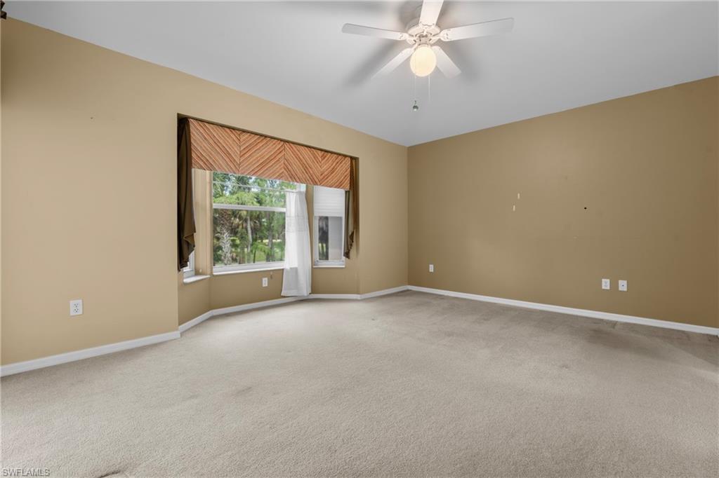 Spacious room featuring neutral carpeting and a wide bay window with a decorative valance and natural light