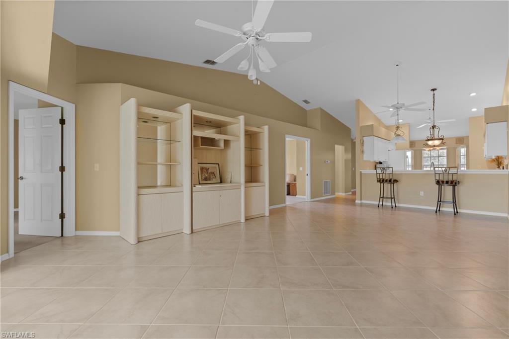 Spacious open-concept interior featuring large format tile flooring, vaulted ceilings, and multiple ceiling fans