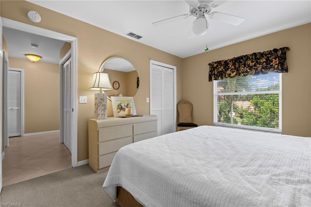 Bedroom featuring a ceiling fan, a window with horizontal blinds, and a built-in closet with bi-fold louvered doors