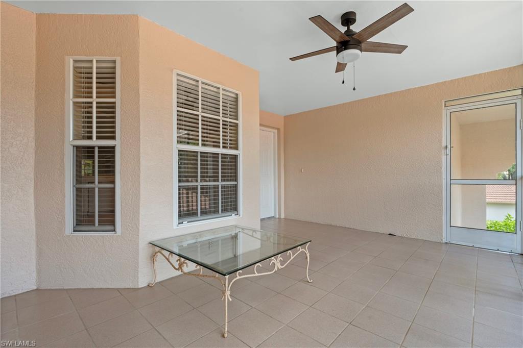Screened outdoor patio featuring light-toned stucco walls, tiled flooring, and a ceiling fan with integrated lighting