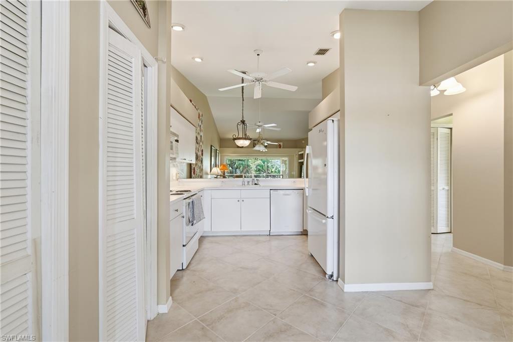 Kitchen with white cabinets, recessed lighting, light countertops, white appliances, and decorative light fixtures
