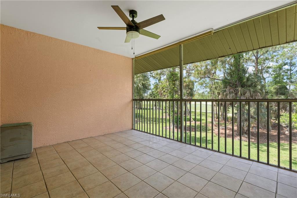 Screened outdoor living area featuring a tile floor, textured wall, and a ceiling fan