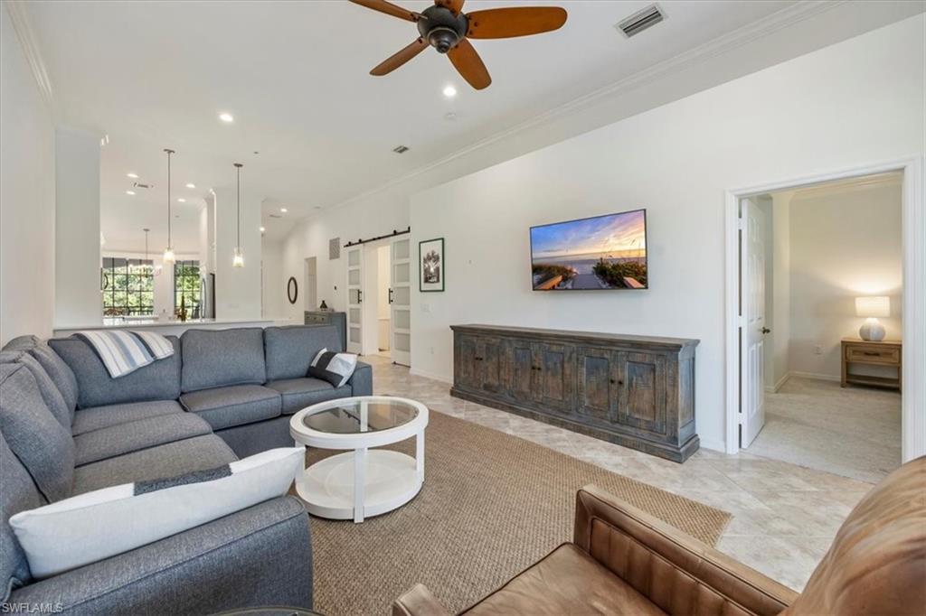 Living area featuring a barn door, recessed lighting, ornamental molding, ceiling fan, and light tile patterned floors