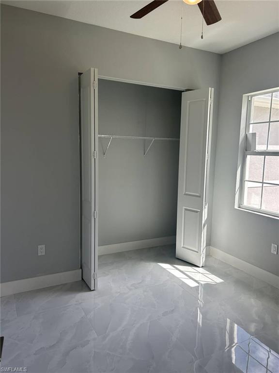 Unfurnished bedroom with ceiling fan and a closet