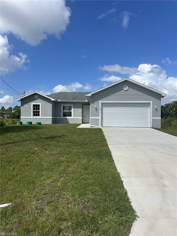 Single story home featuring stucco siding, a front yard, concrete driveway, and a garage