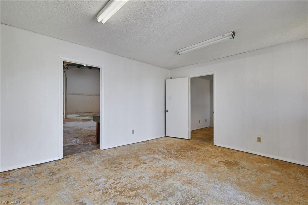 Unfurnished bedroom with a textured ceiling and wooden walls